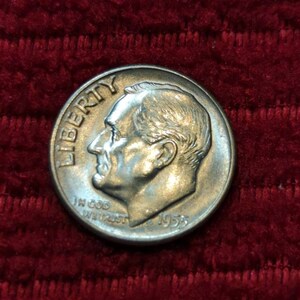 Könnte beinhalten: Eine silberne US-Dime-Münze mit den Worten "Liberty" und "In God We Trust" und dem Jahr "1958" darauf.