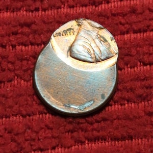 Könnte beinhalten: Ein kupferfarbener US-Penny mit einem beschädigten Rand. Der Münze fehlt ein Teil des oberen Randes und der linken Seite. Das Wort "LIBERTY" ist auf der Münze sichtbar.