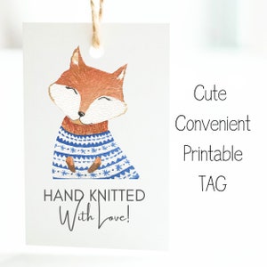 May include: Printable gift tag featuring a cute cartoon fox wearing a blue and white knitted sweater. The tag says "HAND KNITTED With Love!"