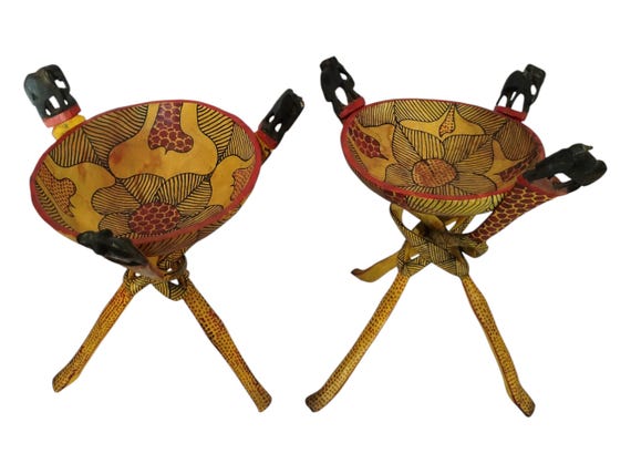 A set of two hand-carved African wooden bowl stands featuring elephant and giraffe motifs — functional sculpture that doubles as conversation-starting safari art.