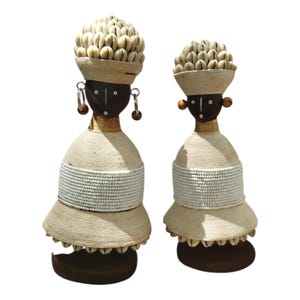 Ein Paar elegante weiße afrikanische Namich-Puppen mit Kaurimuscheln Kunstgeschenkholz-Tischplatte Wohndekor-Regalgeschäft