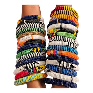 May include: Stacked beaded bracelets in various colors, including blue, white, orange, and green. The bracelets feature intricate patterns and designs, showcasing a vibrant and artistic aesthetic. The bracelets are a fashion accessory.