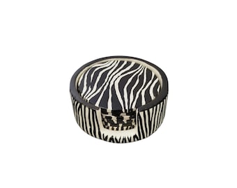 May include: A set of six round coasters with a black and white zebra stripe pattern. The coasters are stored in a matching holder, creating a cohesive and stylish tabletop accessory. The coasters are made of a durable material.