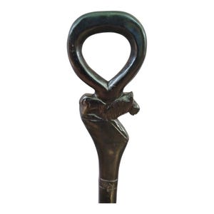 Puede incluir: Bastón de paseo marrón oscuro con una cabeza de león tallada y un asa de bucle. El asa tiene forma de lágrima. El bastón es de madera y tiene un acabado liso. El diseño general es elegante y detallado.