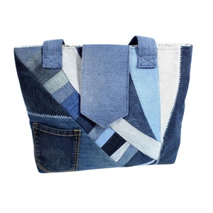 Könnte beinhalten: Eine Patchwork-Denim-Tragetasche in verschiedenen Blautönen. Die Tasche hat eine Vordertasche, einen Klappenverschluss und zwei Griffe. Das Design verwendet verschiedene Denim-Waschungen und -Texturen und erzeugt einen einzigartigen, handgefertigten Look.