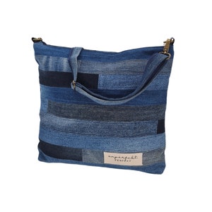 Könnte beinhalten: Eine blaue Jeans-Patchwork-Tragetasche mit einem langen verstellbaren Riemen. Die Tasche hat einen braunen Leder-Patch mit dem Text "unperfect PERFECT" darauf.