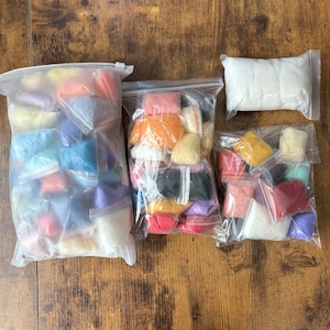 May include: Three clear plastic bags filled with smaller individual resealable pouches containing colorful wool roving. The assortment includes various shades of red, orange, yellow, green, blue, purple, white, and black fibers for crafting projects.