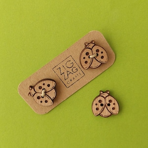Può includere: Tre bottoni di legno a forma di coccinella con dettagli in bianco e nero. I bottoni sono su una carta marrone con il testo "Zig Zag Crafts".