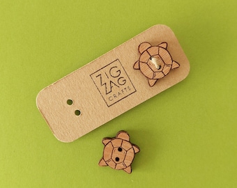 May include: Two wooden turtle buttons with a brown wood finish. The buttons are on a brown card with the text "Zig Zag Crafts".