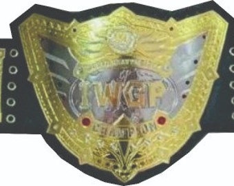 May include: A gold championship belt with a large, ornate center plate featuring a winged design. The belt has two side plates with a smaller winged design and a black leather strap with silver studs.