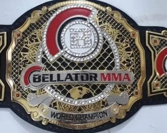 May include: A gold and black championship belt with the words "Bellator MMA World Champion" on the front. The belt has a black leather strap and gold metal plates with a red and white logo.