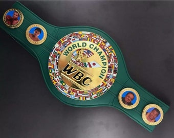 May include: A green leather boxing championship belt with a gold buckle featuring the words "World Champion" and "WBC" surrounded by flags of different countries. The belt has four smaller gold medallions with images of boxers.