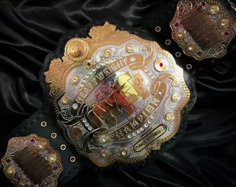 May include: A gold and silver championship belt with the words "Heavyweight Champion" and "IWGP" on the front. The belt is decorated with rhinestones and has a black leather strap.