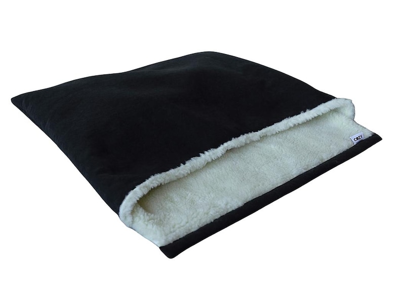 May include: Black pet bed with a white, fluffy interior. The bed has a rectangular shape and a soft, plush exterior. The interior is a contrasting white, creating a cozy space for pets to rest.
