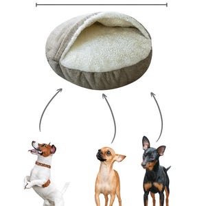 May include: A small, S-sized dog bed with a 70 cm diameter. The bed is a light brown color with a soft, white interior. Three small dogs are pictured below the bed, demonstrating the bed's size.