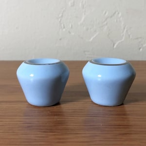 May include: A white ceramic mug with a black handle and the text "But First, Coffee" in a black, bold font. The mug is sitting on a wooden surface. The mug is approximately 4 inches tall.