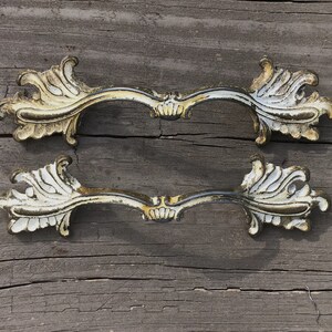 May include: Two ornate gold and white metal drawer pulls with a decorative floral design.