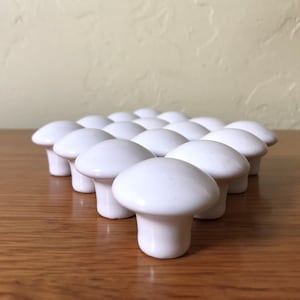 May include: A group of 18 white ceramic mushroom-shaped drawer knobs.
