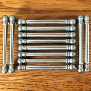 May include: Ten silver drawer pulls with rounded ends. The pulls are arranged in two rows of five.