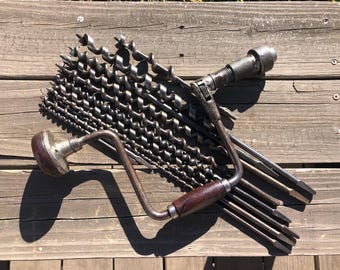 May include: A vintage hand drill with a wooden handle and a set of drill bits. The drill bits are made of metal and have different sizes. The drill is a useful tool for woodworking and other DIY projects.