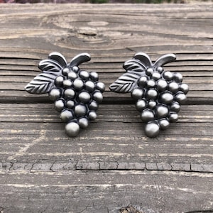 May include: Two silver-toned metal grape cluster drawer pulls with a leaf design.