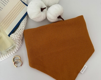 May include: A mustard yellow waffle-textured bandana with the text "BARK & MAIN" printed on the bottom right corner.