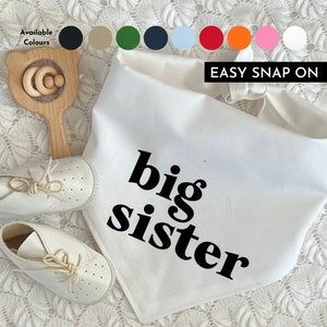 May include: White cotton bandana with the text "big sister" in black. The bandana has a snap closure and is available in multiple colours.