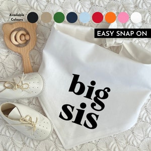 May include: White bandana with the text "big sis" in black bold letters. The bandana has an easy snap on closure. Available colours include black, beige, green, navy, light blue, red, orange, pink, and white.