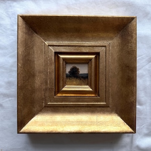Peut inclure: Une peinture de paysage carrée représentant la silhouette d'un arbre sombre sur un ciel atténué, encadrée par un large cadre doré métallique à plusieurs niveaux avec une finition texturée. L'œuvre montre un champ et un horizon.