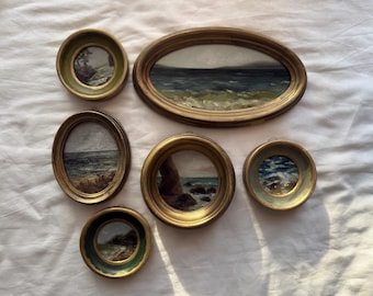May include: Set of six gold-toned picture frames with various seascapes and landscapes. The frames are oval and round, with a variety of sizes.