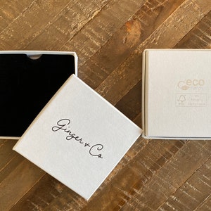 May include: Two white gift boxes, one with a black interior and the other with the text "Ginger + Co" printed on the top. The box with the text also has a small, gray label with the text "Ceco Energy" and "FSC Recycled" printed on it.