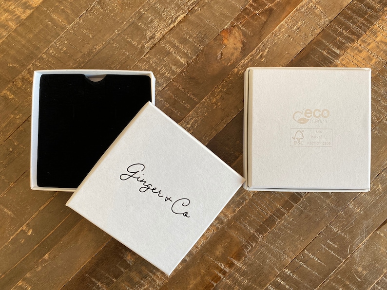 May include: Two white gift boxes, one with a black interior and the other with the text "Ginger + Co" printed on the top. The box with the text also has a small, gray label with the text "Ceco Energy" and "FSC Recycled" printed on it.