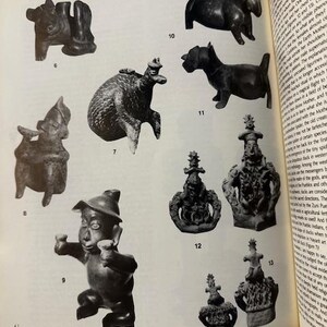 May include: A page from a book featuring various dark-colored, antique-style sculptures. The sculptures include animal figures, human-like figurines, and ornate, crown-like objects. The page is open, with text visible on the right side.