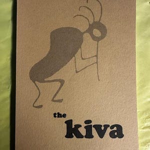 May include: A tan booklet featuring a dark grey Kokopelli figure. The words "the kiva" are in bold black, with "Spring 1983" beneath. The booklet has a slightly worn appearance, with a textured surface.