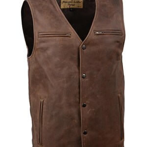 May include: A brown leather vest with a V-neck and button closure. The vest has two zippered chest pockets and two lower pockets. The leather has a distressed look, and the vest has a label that reads "Milwaukee Leather Vintage".
