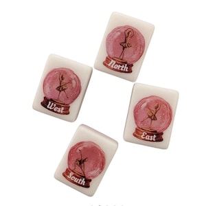 May include: Four white tiles featuring a ballerina in a pink snow globe design. Each tile is labelled with a compass direction: North, South, East, and West. The tiles are arranged in a circular pattern against a white backdrop.