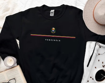 May include: Black sweatshirt with a colorful Venezuelan coat of arms and the word "VENEZUELA" printed on the front.