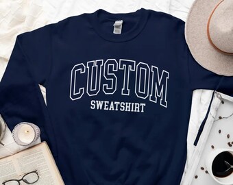 May include: A navy blue sweatshirt with the text "CUSTOM SWEATSHIRT" in white.