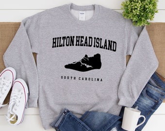 May include: A gray sweatshirt with the text "HILTON HEAD ISLAND" and "SOUTH CAROLINA" in black lettering. The island is depicted as a black silhouette of a shoe.