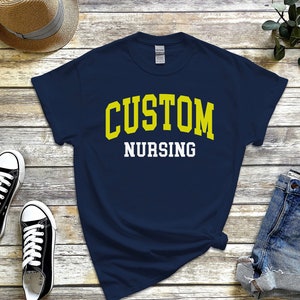 May include: A navy blue t-shirt with the text "CUSTOM NURSING" in yellow and white letters.