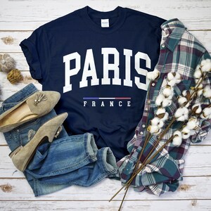 May include: A navy blue t-shirt with white text that reads "PARIS FRANCE" with the French flag in between the words.