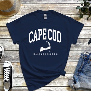 May include: A navy blue t-shirt with a white graphic of the Cape Cod outline and the text "CAPE COD MASSACHUSETTS".