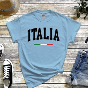 May include: Light blue t-shirt with the word "ITALIA" in black text and the Italian flag colors in a thin stripe below the word.