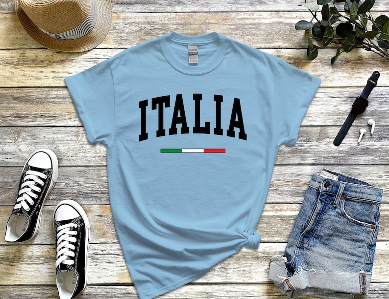 May include: Light blue t-shirt with the word "ITALIA" in black text and the Italian flag colors in a thin stripe below the word.