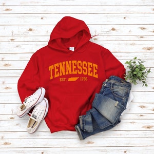 May include: Red hooded sweatshirt with the text "TENNESSEE EST. 1796" in orange with an outline of the state of Tennessee in orange.