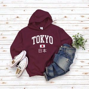 May include: Burgundy hooded sweatshirt with white text that says "TOKYO" and a Japanese flag with the text "日本" underneath.