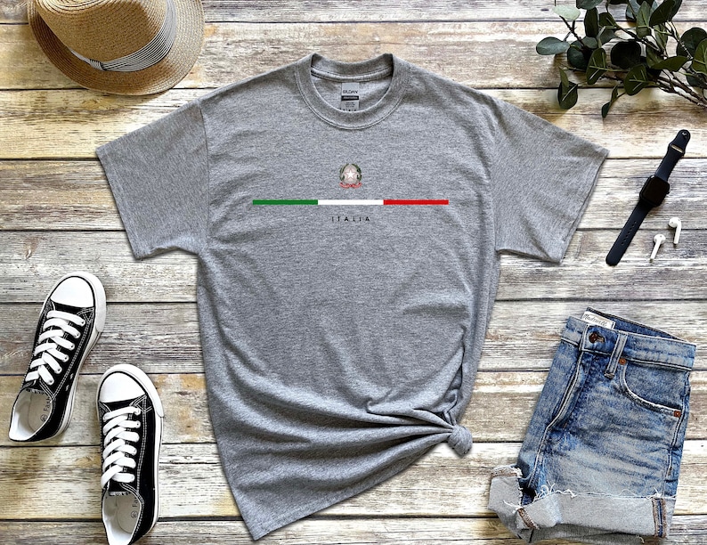 Puede incluir: Una camiseta gris con una peque&ntilde;a bandera italiana y la palabra "ITALIA" impresa en la parte delantera.