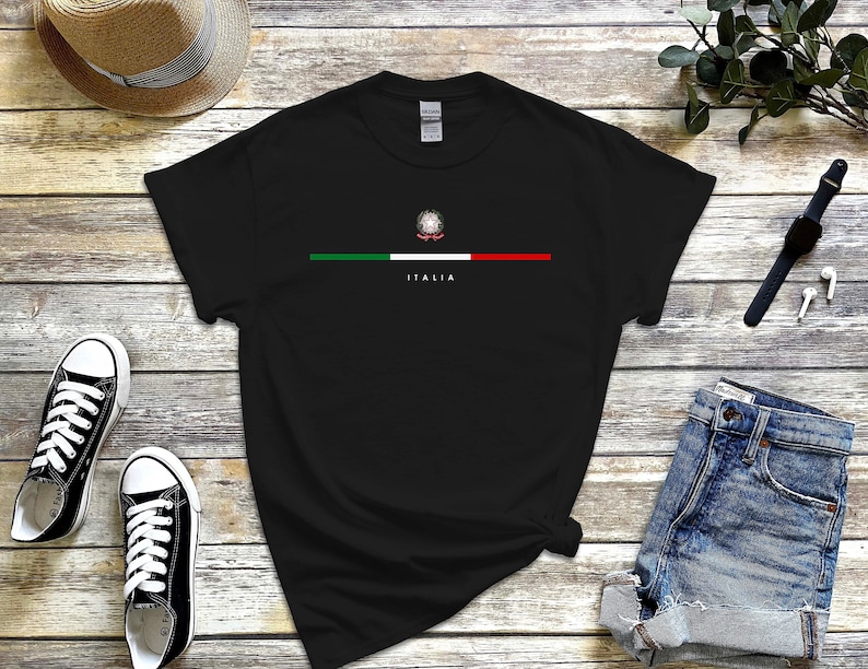 Puede incluir: Camiseta negra con una franja verde, blanca y roja a trav&eacute;s del pecho. La franja presenta un peque&ntilde;o emblema de la bandera italiana y la palabra "ITALIA" en texto blanco.