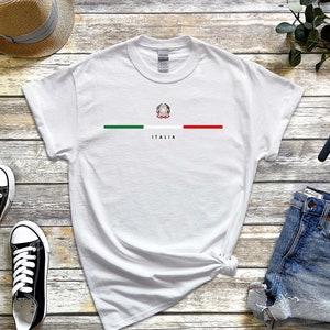 Puede incluir: Camiseta blanca con una franja verde, blanca y roja en el pecho. Los colores de la bandera italiana est&aacute;n centrados con el escudo de armas italiano en el medio. La palabra "ITALIA" est&aacute; impresa debajo de la franja.