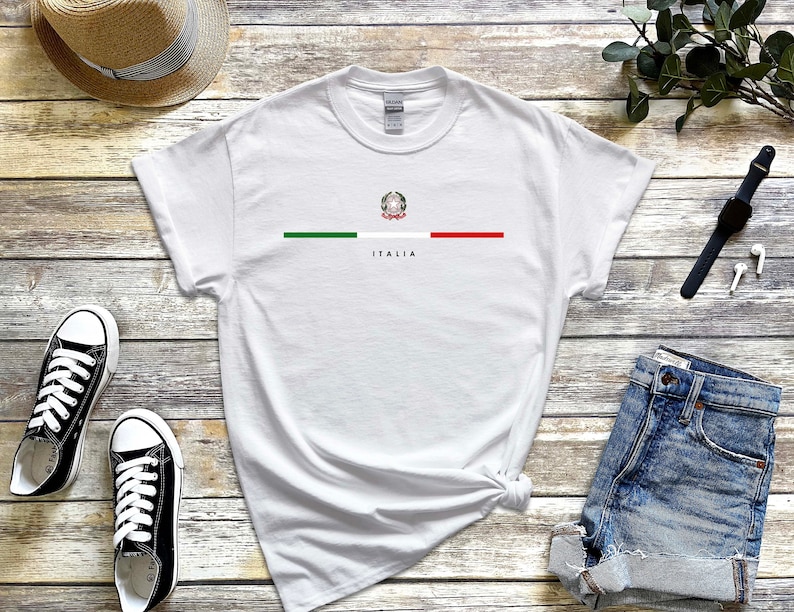 Puede incluir: Camiseta blanca con una franja verde, blanca y roja en el pecho. Los colores de la bandera italiana est&aacute;n centrados con el escudo de armas italiano en el medio. La palabra "ITALIA" est&aacute; impresa debajo de la franja.